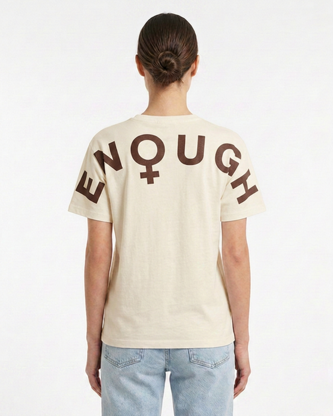 Person wearing a beige t-shirt with 'ENOUGH' printed on the back against a white background