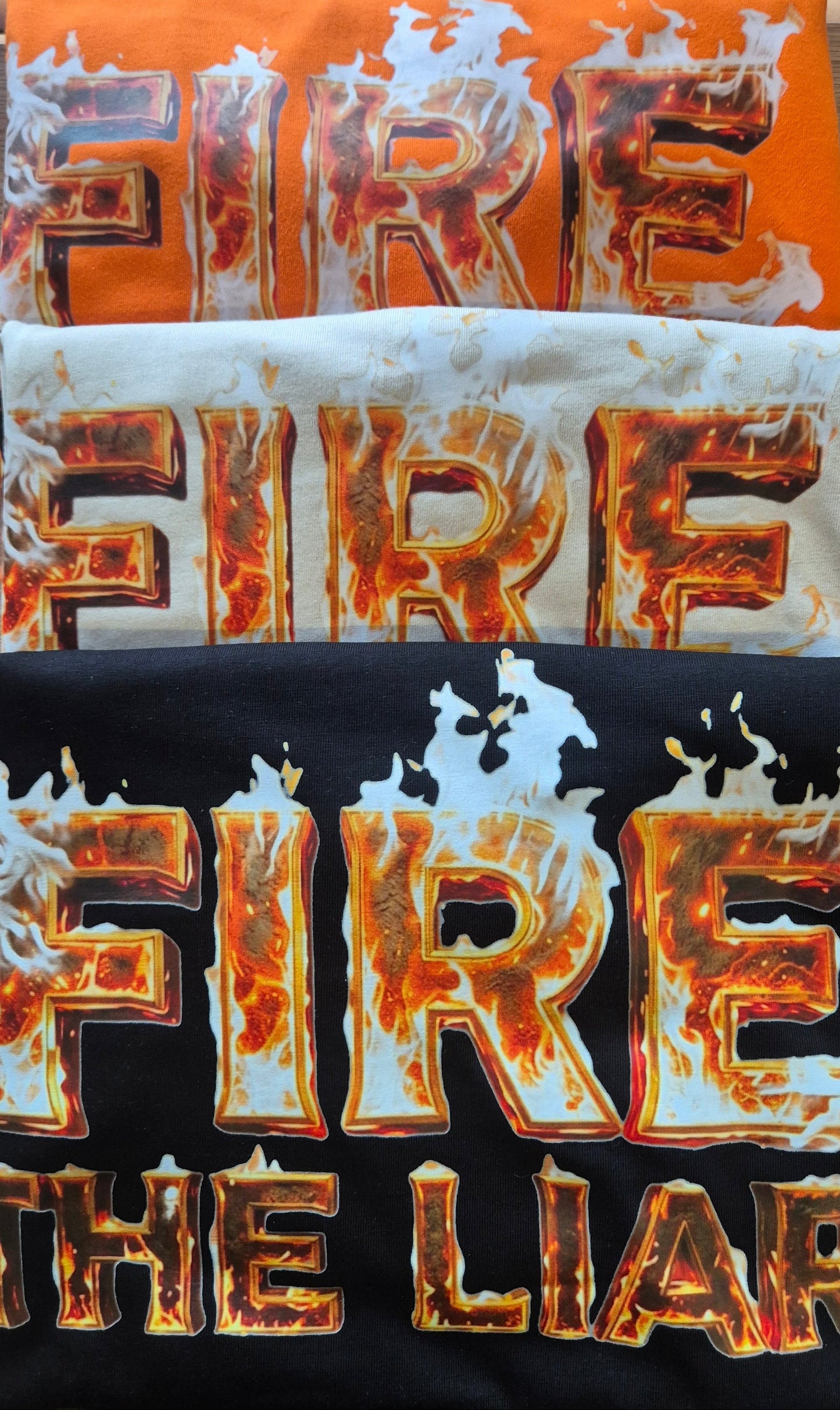 Three t-shirts with 'LIAR' text in a distressed, fire-like design on an orange, white, and black background.